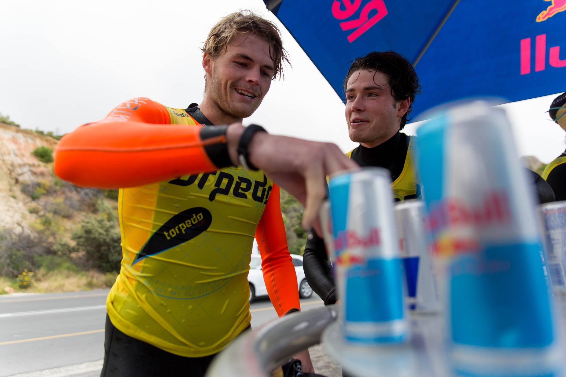Two swimrunners grabbing Red Bull at a roadside aid station