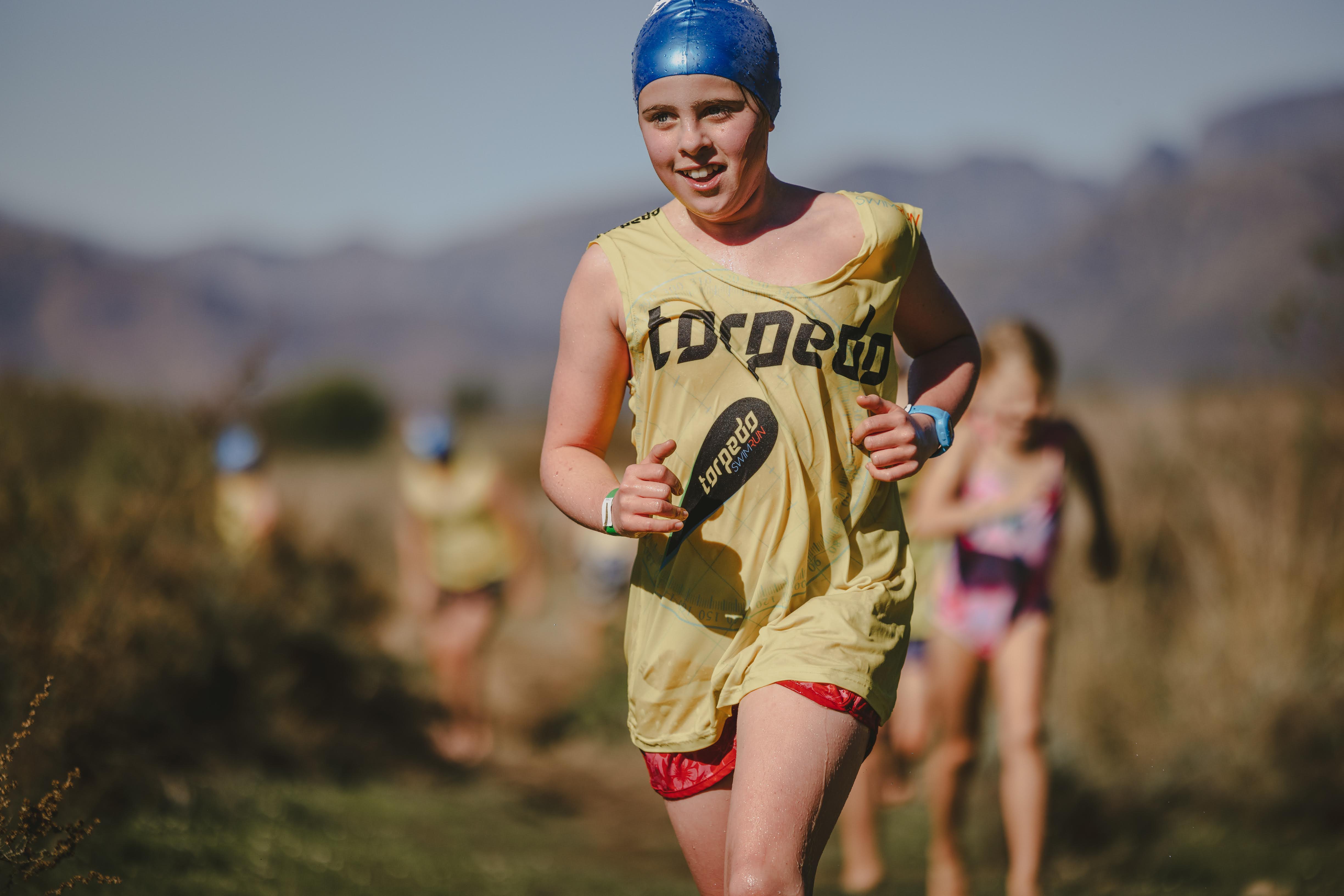 Close-up of a boy in a blue cap and yellow Torpedo vest running with a big smile