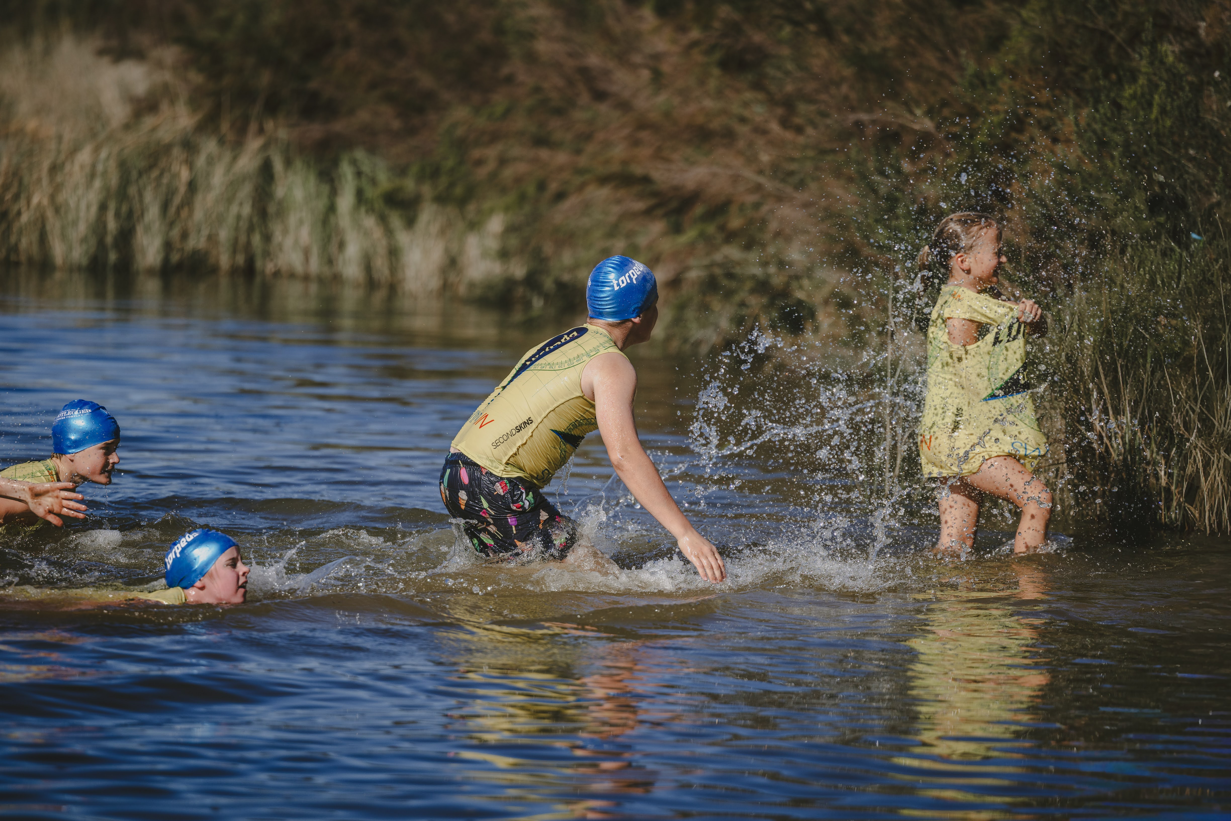 Kids playing and splashing in the shallows of the dam, water spraying in the sunlight