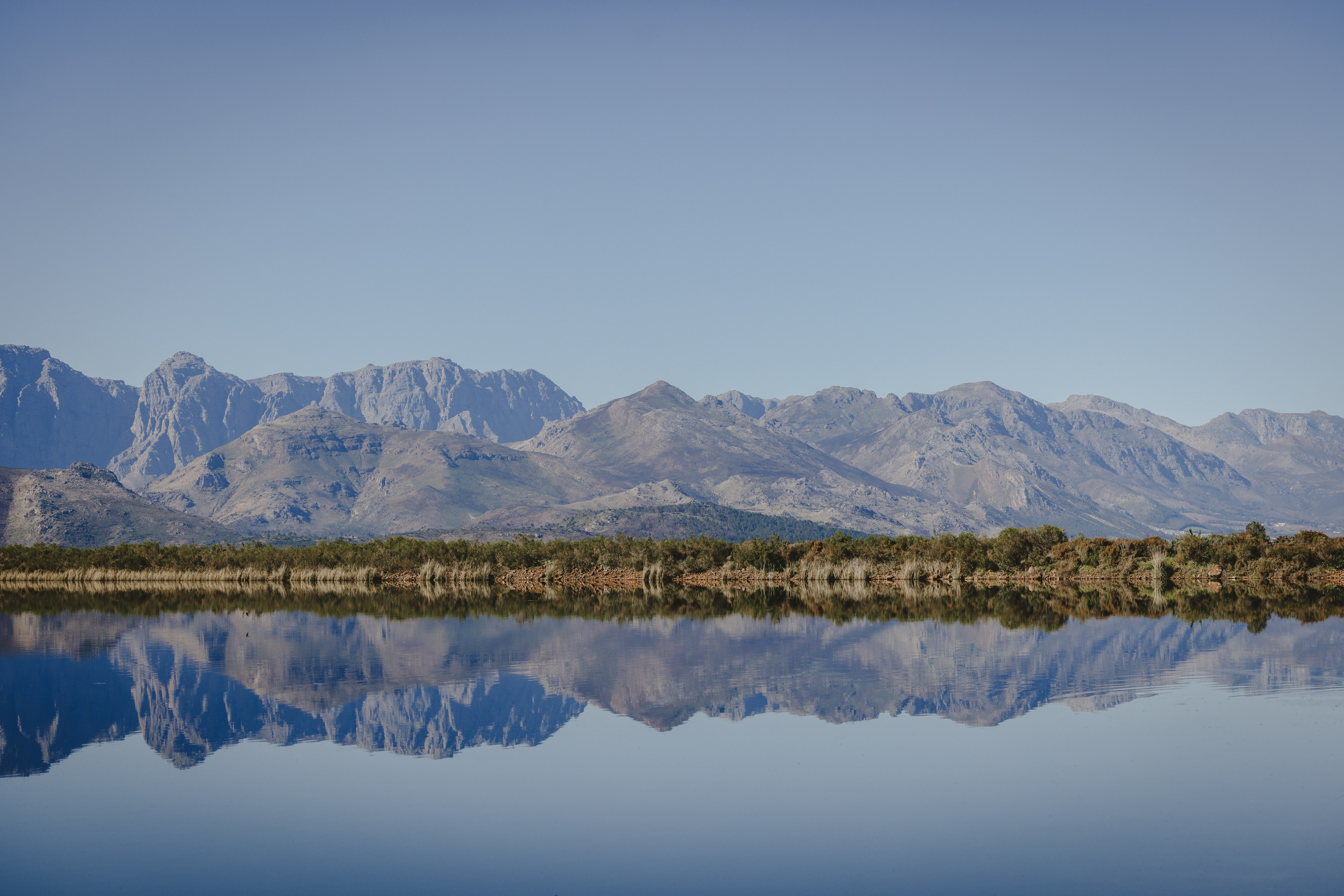 The Simonsberg mountains mirrored in the glassy Plaisir dam at dawn